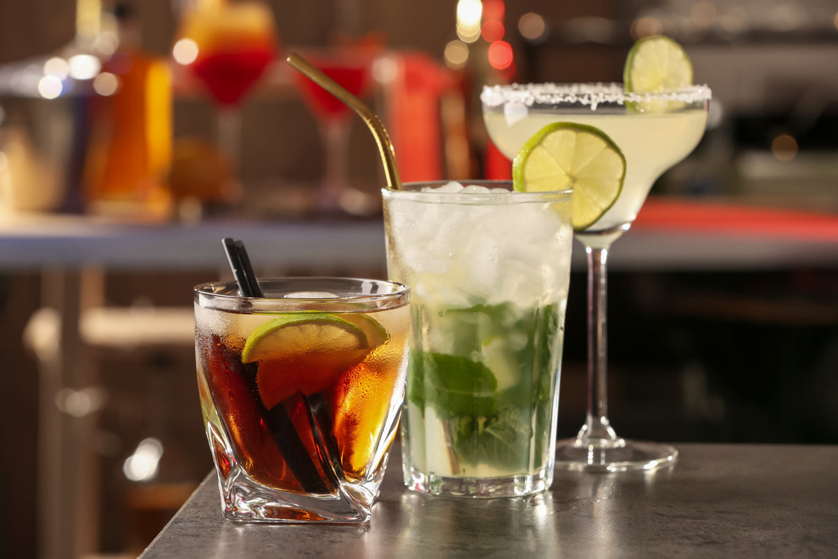 Different delicious rum cocktails on grey table in bar